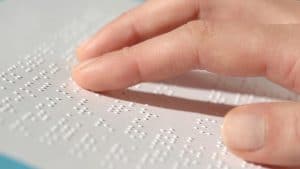 Mano de persona leyendo la escritura braille
